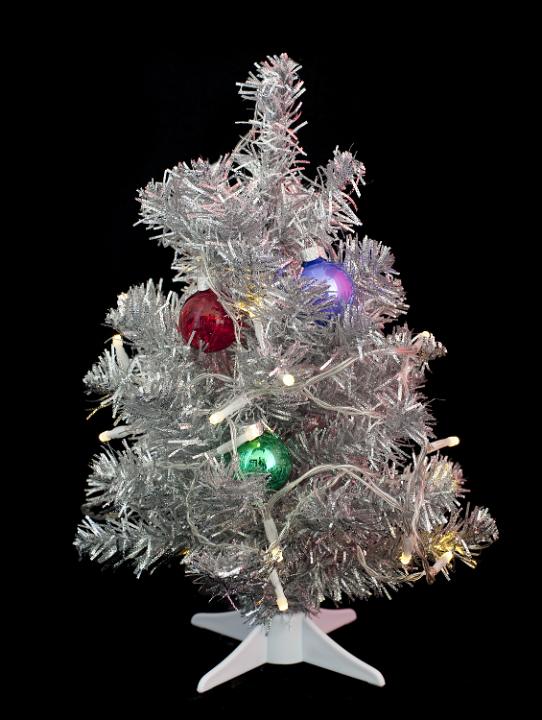 a small artificial silver christmas tree with lights and decorations