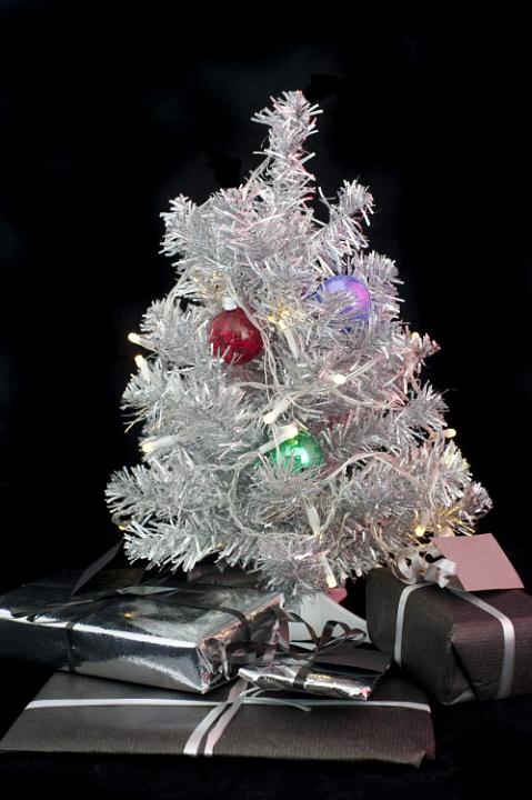 a silver tinsel christmas tree and decorations with gifts beneath