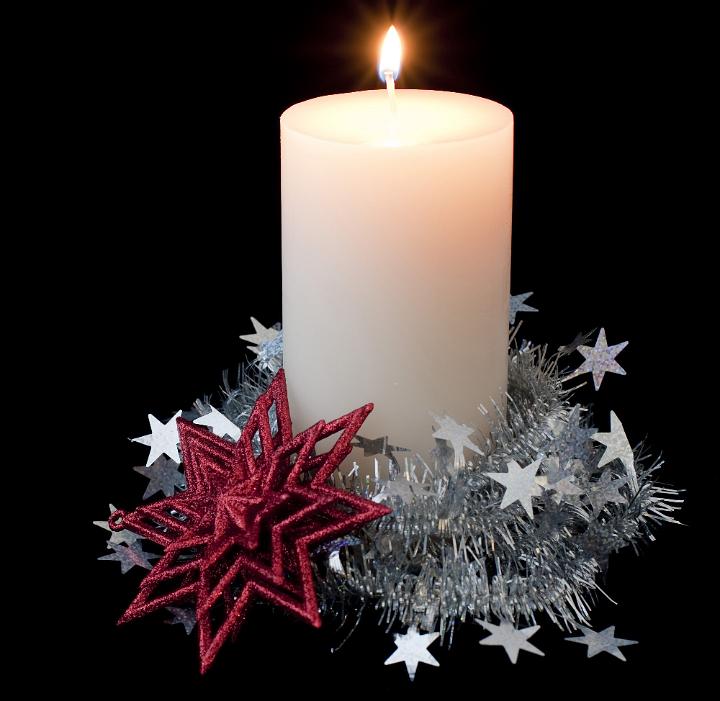 a burning pillar candle surrounded by seasonal decorations