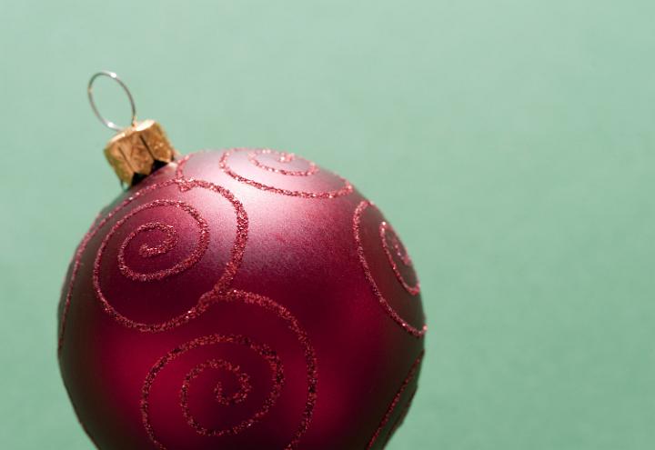 Close-up of red decorative Christmas ball on green background