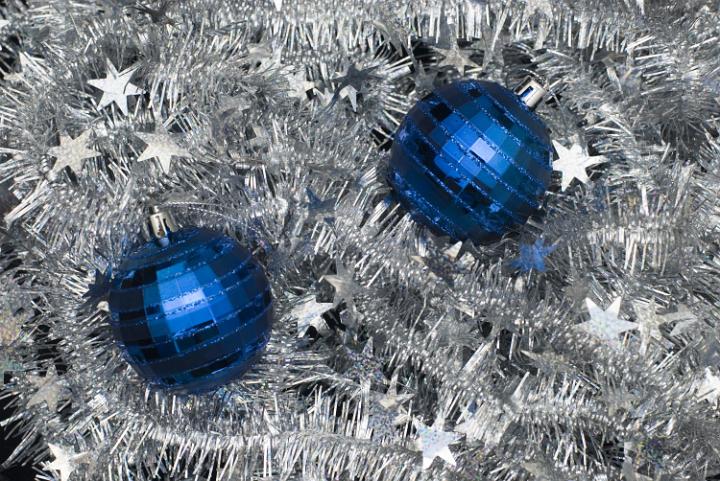 a bed of silver tinsel with blue christmas baubles on top