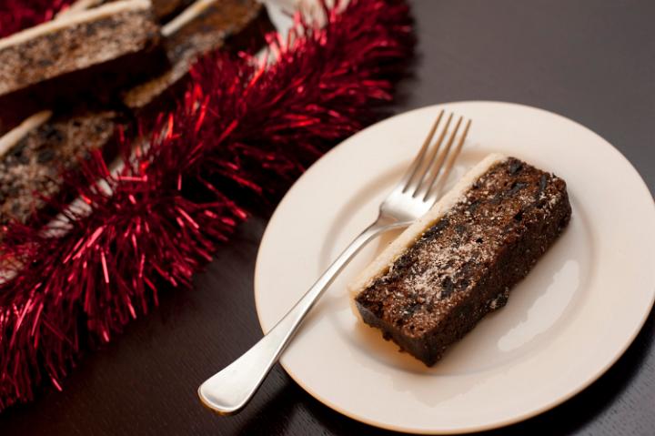 Slice of Christmas fruit cake with a marzipan and almond paste icing served on a plate on a festive table, high angle view