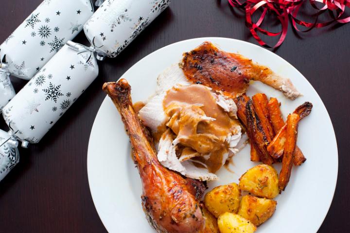 Tasty roast Christmas dinner with turkey, potatoes and carrots topped with gravy, overhead view