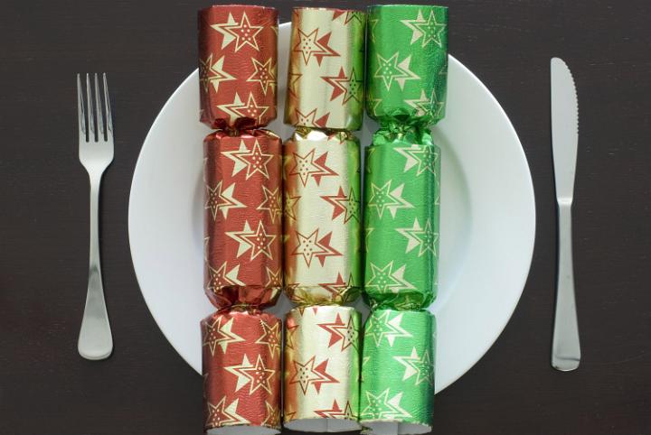 A christmas place setting, a plate with three different coloured crackers