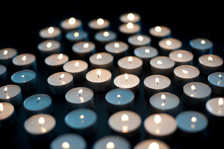 Array of small round burning candles celebrating the Christmas faith against a dark background