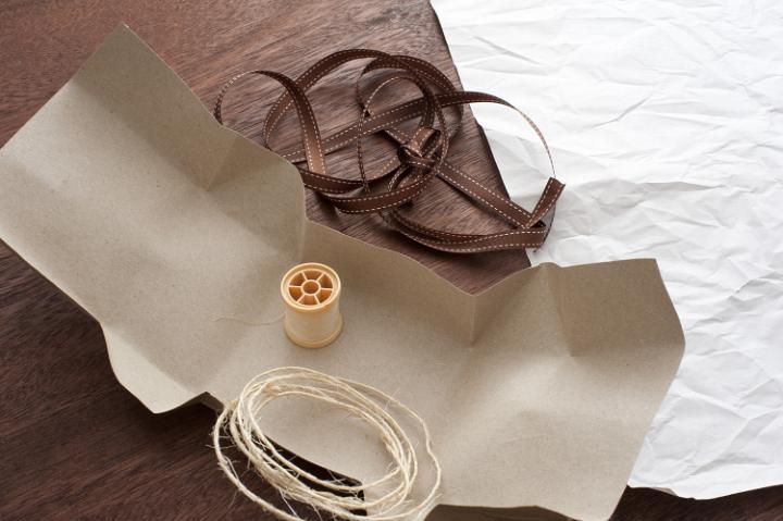 Close-up of wrapping paper and ribbon lying on wooden table. From above