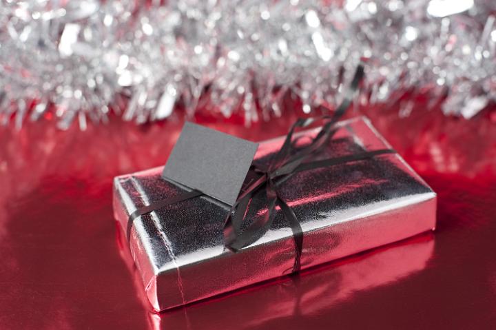 a single wrapped gift with ribbon and tinsel in the background