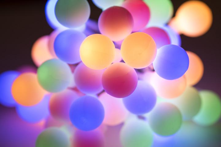 Colorful array of festive multicolored illuminated Christmas ball lights shining in the darkness in a close up Xmas background