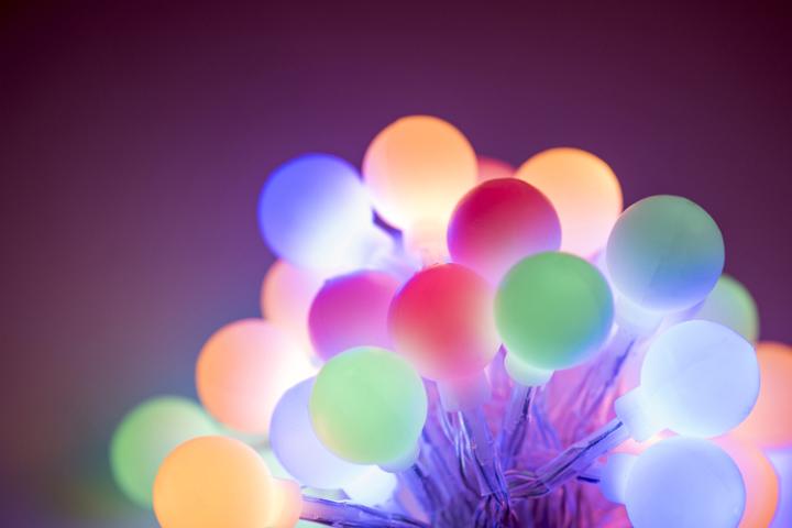 Glowing cluster of round Christmas berry lights in assorted muted hues shining in the darkness for a festive holiday background