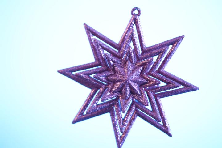 a glitter christmas star tree ornament pictured with a cross processed effect