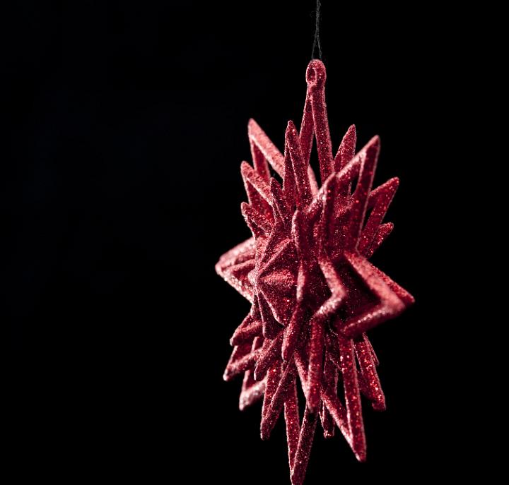 a red christmas star tree ornament on a black background