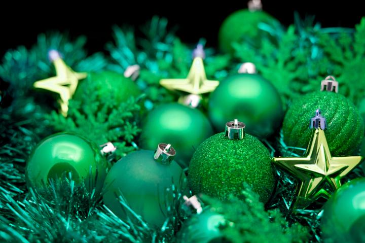Green and gold Christmas baubles and stars nestling in sparkling tinsel for a decorative seasonal background