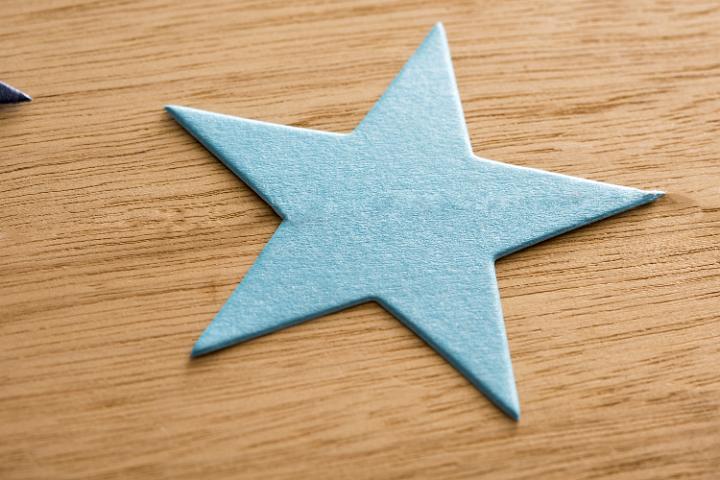 Blue green Christmas paper star on a textured wooden background with woodgrain