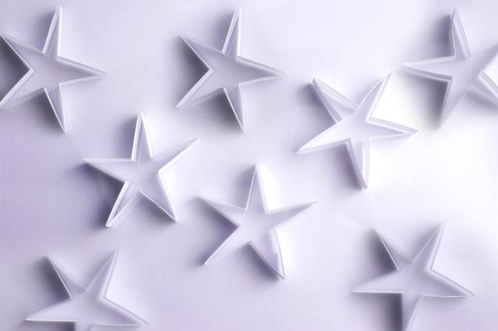 Scattered paper stars on a white background form a lovely delicate backdrop for your Christmas message