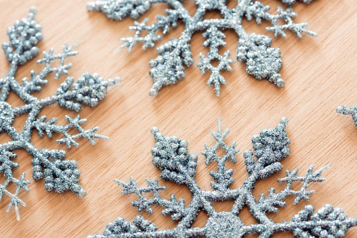 Tasteful ornamental blue glitter snowflake decorations for Christmas celebrations arranged on a wooden background in a high angle view