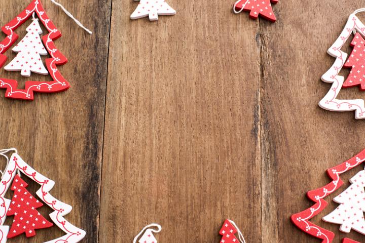 Frame of wooden Christmas tree decorations with colorful red and white star patterns on a rustic wood background with copy space