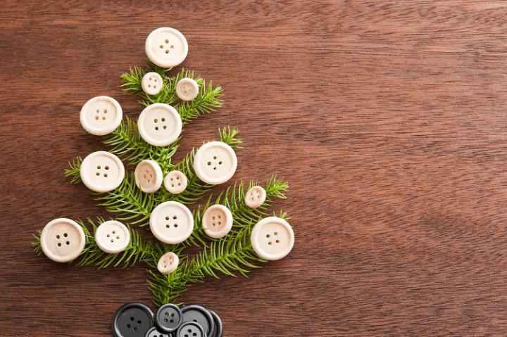 tree branch decorated with buttons on wooden surface, christmas crafts concept