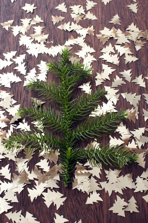Cut out handmade golden Christmas trees and fir tree branch on wooden table