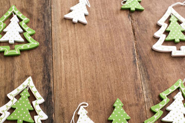 Festive frame of wooden green Christmas tree ornaments in the shape of traditional Xmas trees on a rustic wood background with copy space