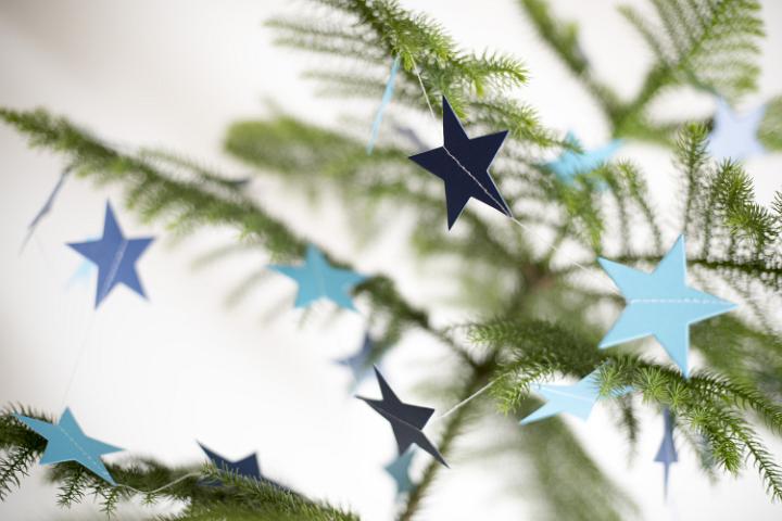Close up shot of some paper stars hanging on a Christmas tree