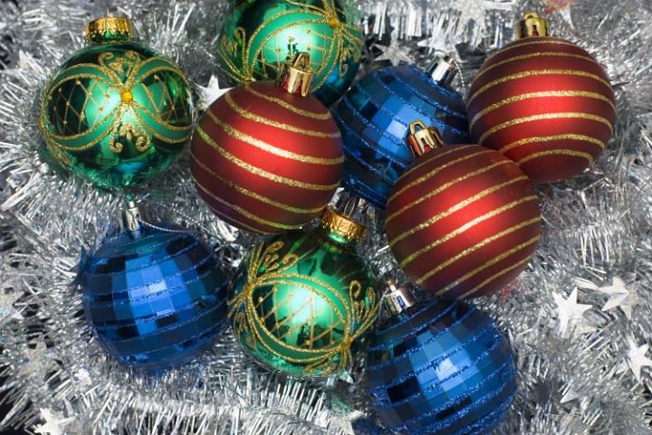 red green and blue christmas glass baubles on a background of silver tinsel