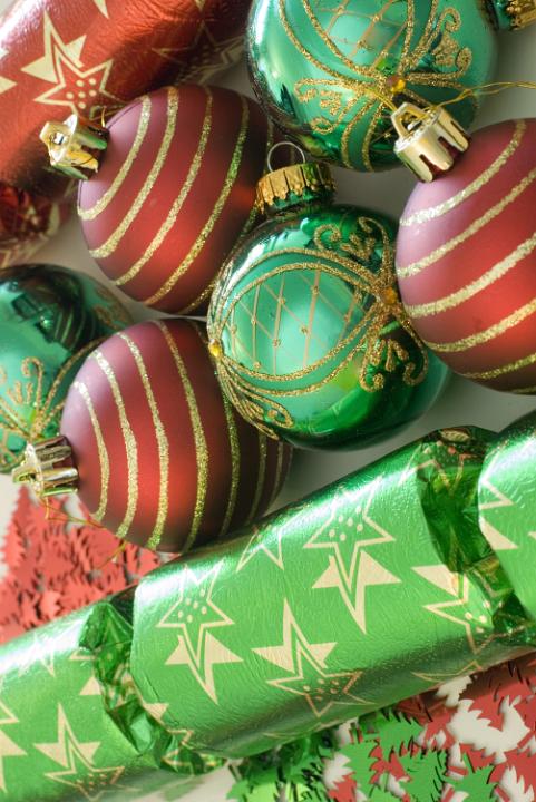 an assortment of red and green coloured christmas baubles and crackers