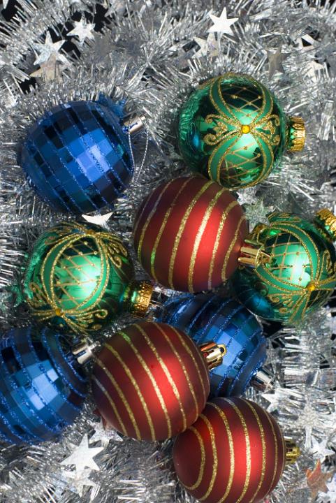 red green and blue christmas baubles on a background of tinsel creates a colorful christmas backdrop