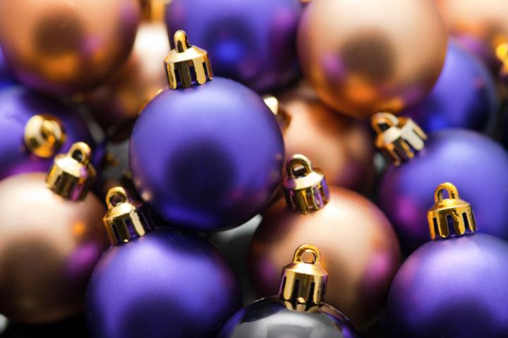 a narrow depth of field image of purple and gold coloured plain christmas baubles