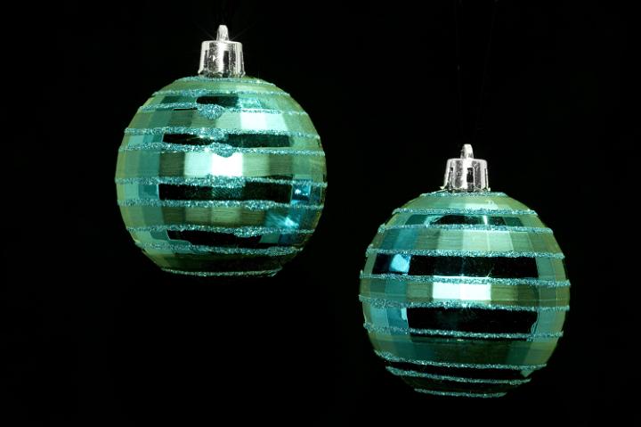two hanging green christmas baubles isolated on a black backdrop