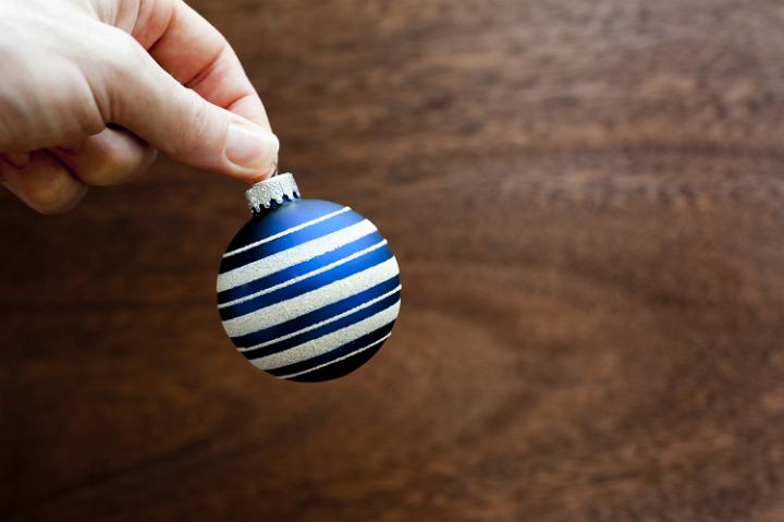 holding Christmas glass bauble on wooden background