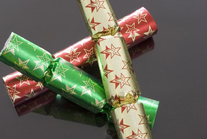 Three different coloured chrismas crackers on a dark polished background
