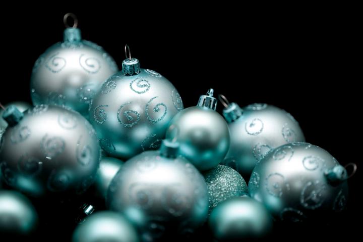glittering light blue green coloured silvery christmas baubles with a back backgorund and space for text