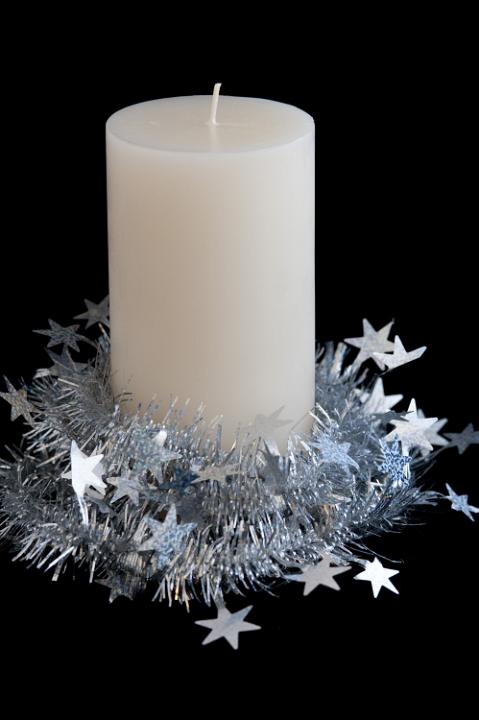 a new christmas candle wrapped in tinsel on a black background