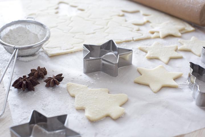 Work space for baking with cookie sheet, rolling pin and shaped cutters beside star anise