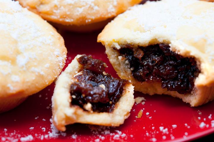 Close up of a delicious freshly baked Christmas mince pie with a rich fruit filling and golden crust broken open to reveal the filling
