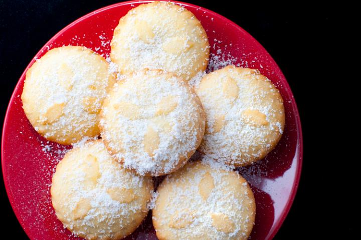 Overhead view of a plate of store bought Christmas mince pies arranged neatly on a festive red plate and sprinkled with sugar