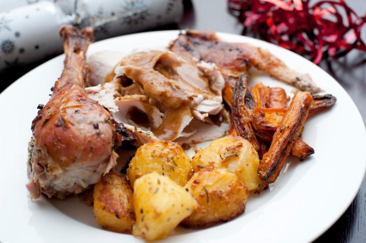 Traditional festive dinner of roast turkey and vegetables to celebrate Christmas, New Year or Thanksgiving served on a plate topped with gravy