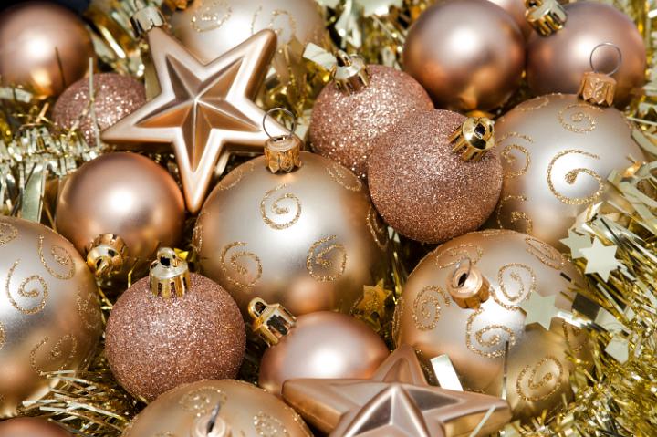 Gold Christms baubles and stars nestling on a bed of glittering gold tinsel giving a luxurious festive background