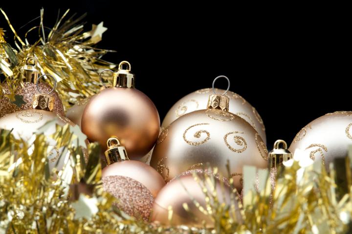 decorative background with gold coloured baubles and tinsel garland, space for text in the upper right