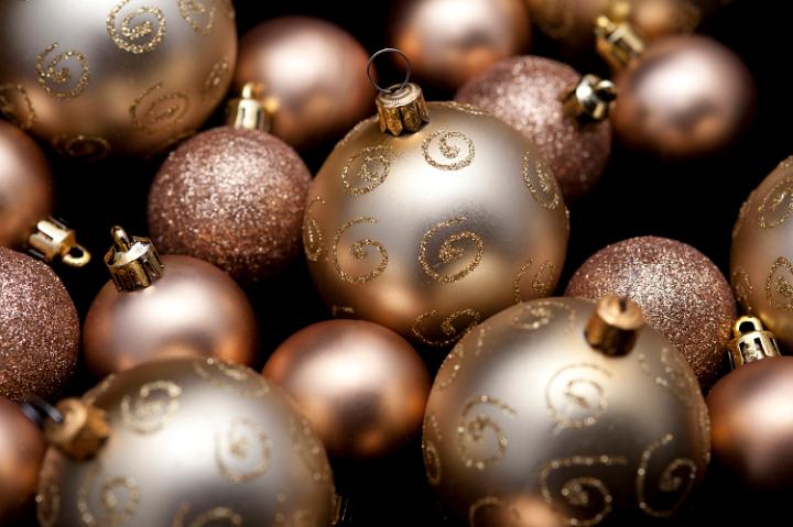 an random assortment of various types of gold coloured christmas baubles on a black background