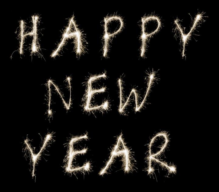Happy New Year text written in fiery white sparklers on a black background to welcome in the new year