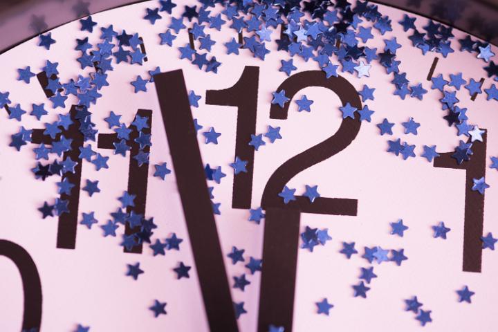 Countdown to midnight on New Years Eve with a close up view of a clock dial decorated with stars with the hands approaching the twelve
