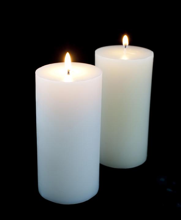 large white candles burning against a dark backdrop