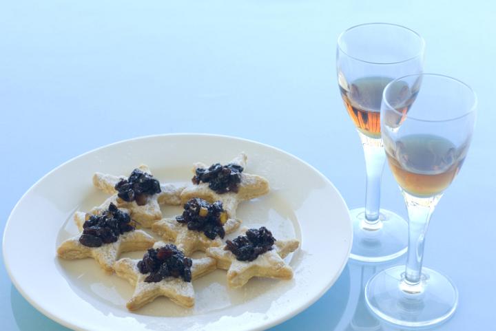 a plate of christmas snack appetisers, sweet crust pastry and mincemeat with glasses of sherry