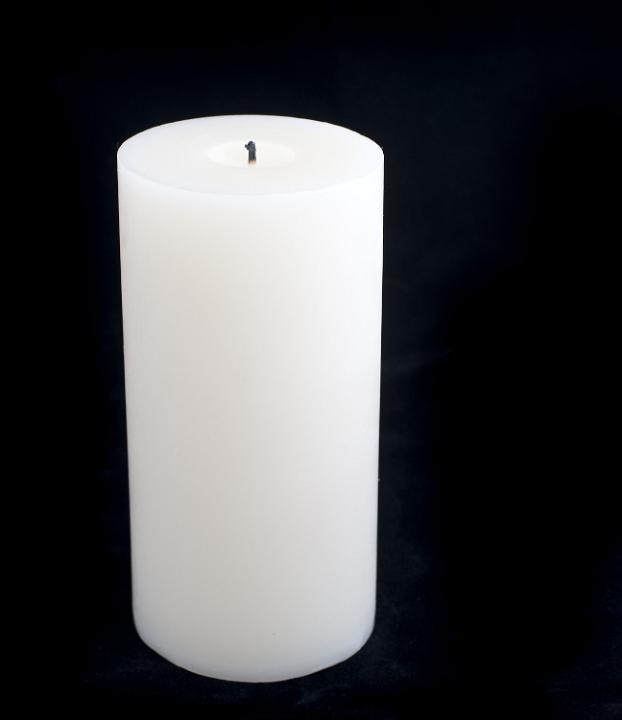 a large pillar candle unlit on a black background