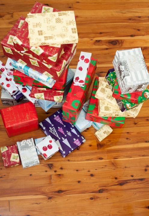 Pile of colourful gift-wrapped Christmas gifts in all shapes and sizes in multicoloured giftwrap with traditional seasonal patterns, high angle view on a hardwood floor