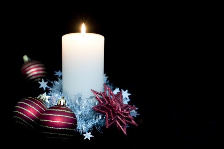 a large candle surrounded by seasonal decorations with lots of copyspace to the right