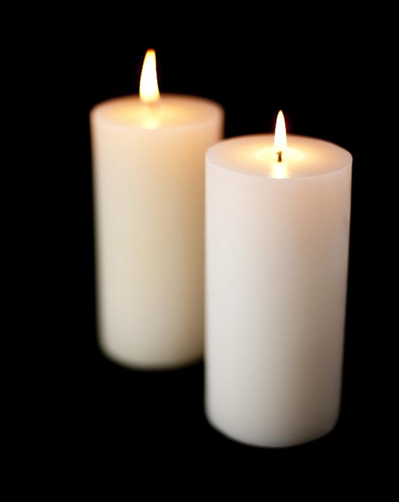 large white candles burning against a dark backdrop, pictured with a narrow depth of field to create a cosy homely effect