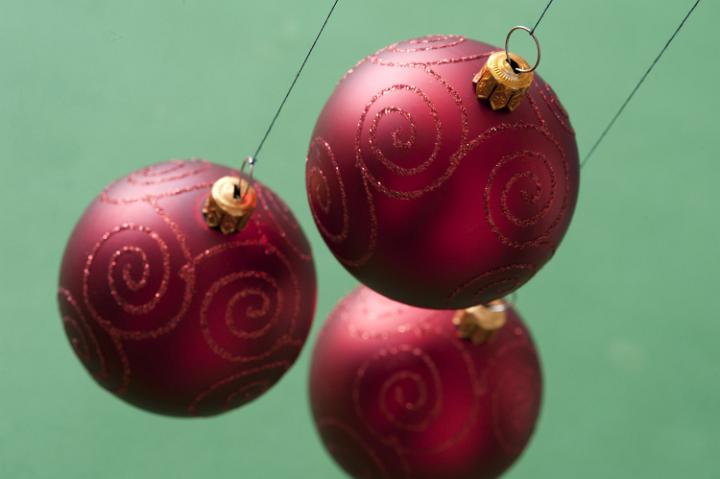 Three red Christmas balls hanging on green background