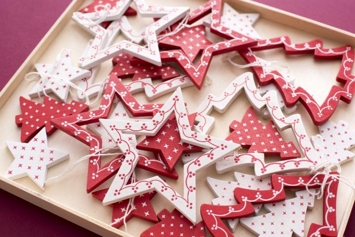 Tray filled with festive red and white wooden Christmas tree ornaments in the shape of stars and trees viewed high angle for a seasonal background